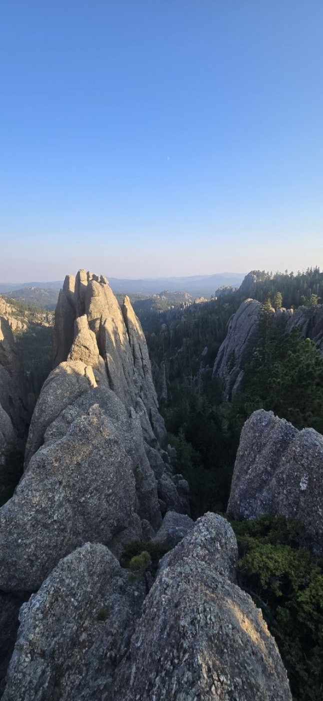 A close-up view among the granite spires with forested ridgelines stretching into the distance