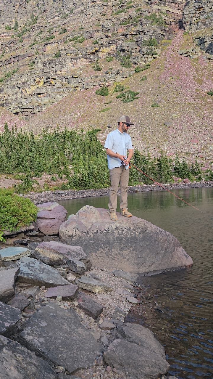 Fly fishing from a large boulder at the edge of Cobalt Lake, Glacier National Park.
