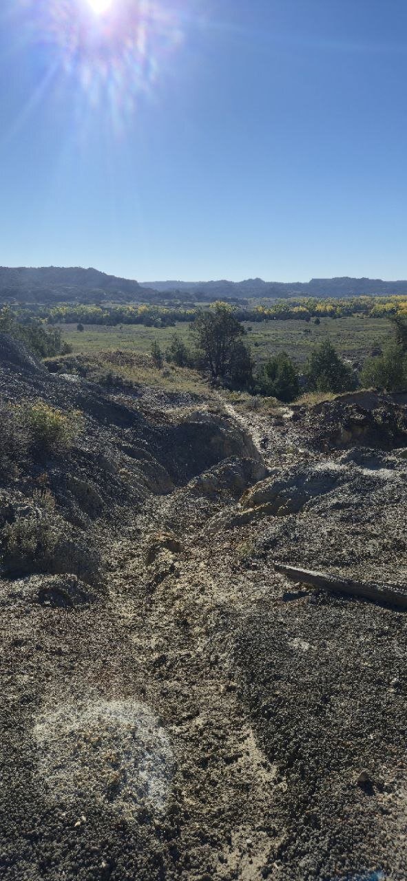A rocky, eroded wash cutting down through the badlands toward the river valley.